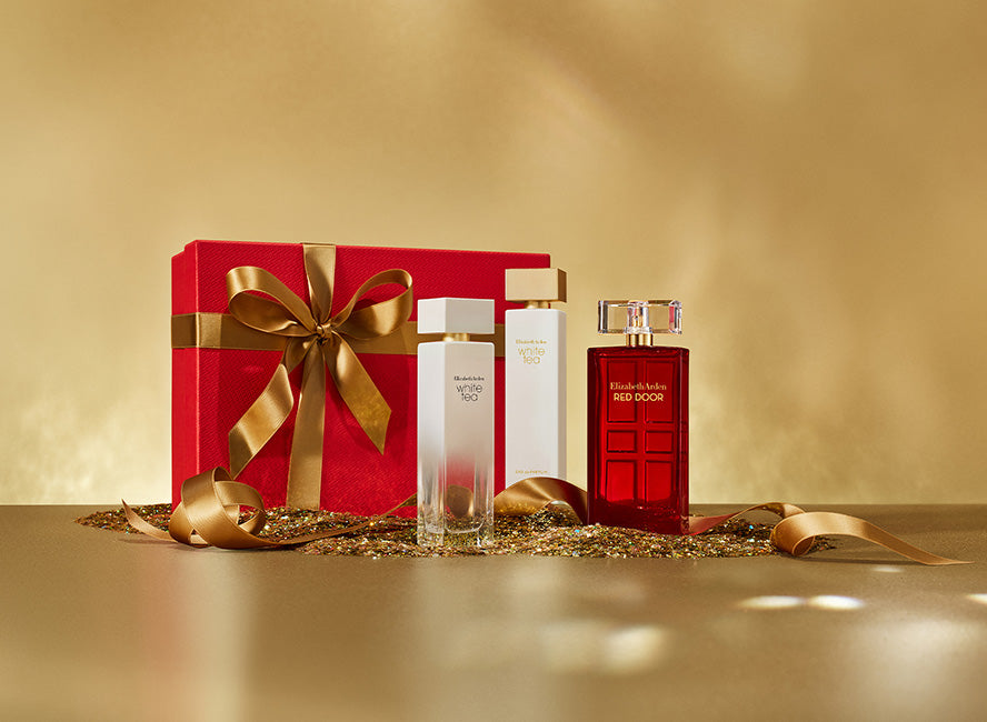 a gift box on a gold surface with a soft beige background featured with 3 Elizabeth Arden Fragrances