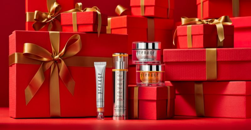 Red gift boxes with gold ribbons and skincare products on a red background