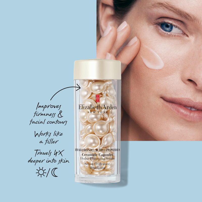 Woman (model) with new HA Capsules Serum on a light blue background. She is swiping the silky serum on her face while copy calls out that the product improves firmness & facial contours, works like a filler, travels 4x deeper into skin and can be used day or night. 